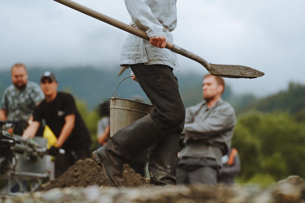 A team of individuals working outdoors on a film set with mountain and forest backdrop.