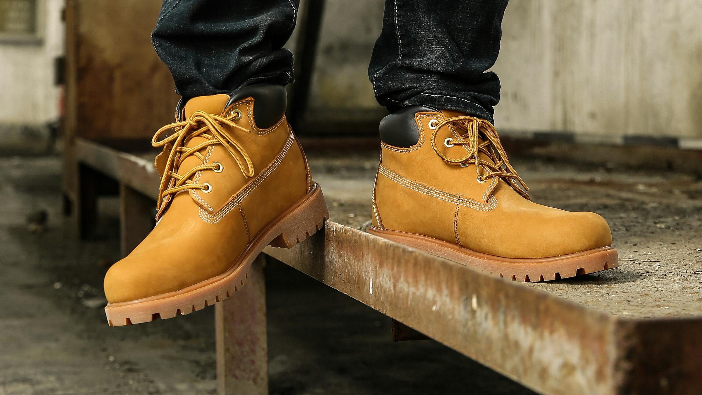 Fashionable tan boots on a rustic metal beam indoors. Urban style captured in a vertical shot.