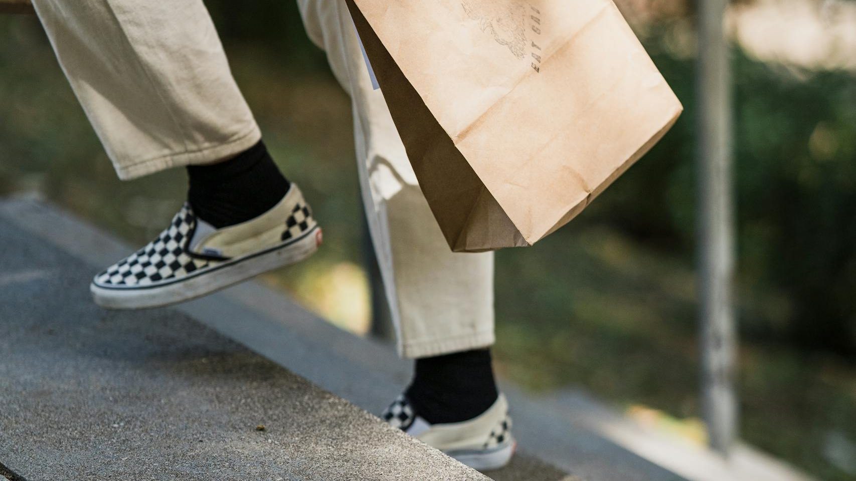 Side view of a woman carrying a paper bag while climbing stairs outdoors, showcasing casual lifestyle.